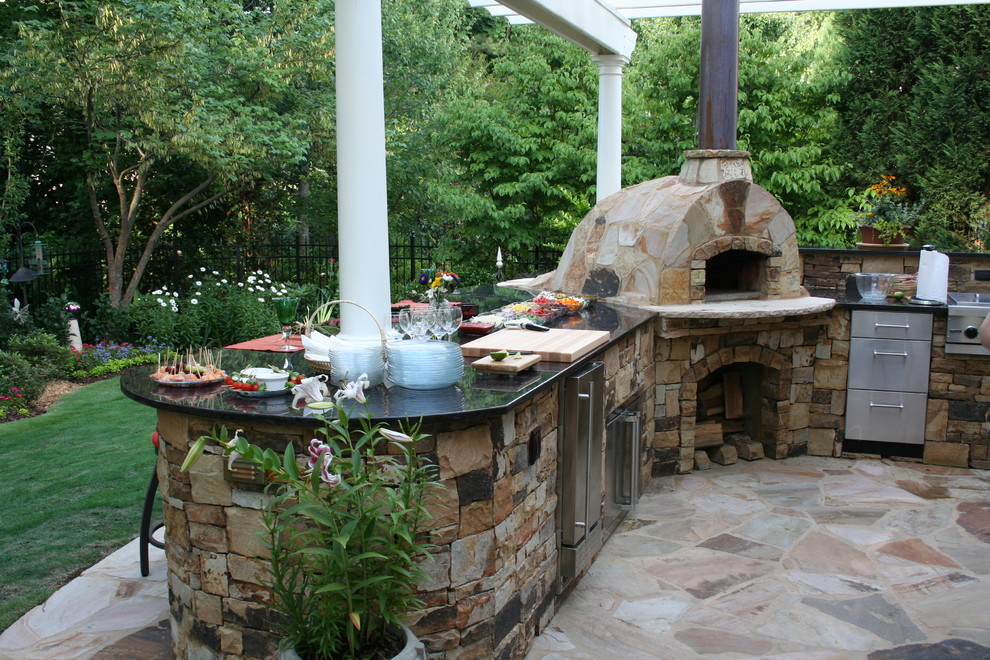 Foto di un grande patio o portico tradizionale dietro casa con pavimentazioni in pietra naturale e una pergola