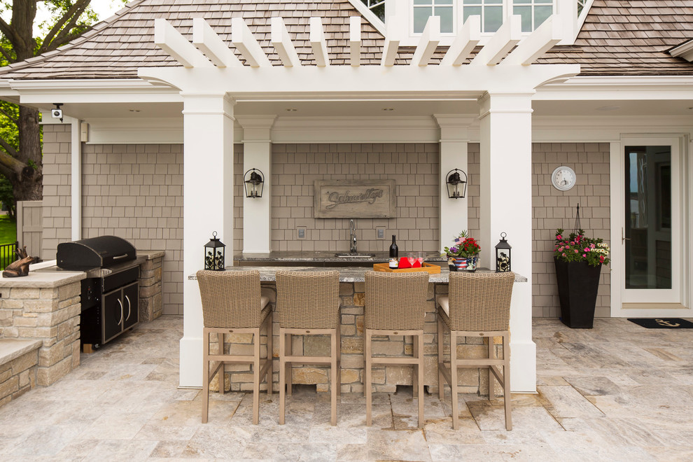 Large arts and crafts backyard stone patio kitchen photo in Minneapolis with a pergola