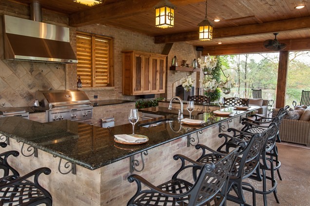 Cette image montre une grande terrasse arrière chalet avec une cuisine d'été, une dalle de béton et une extension de toiture.