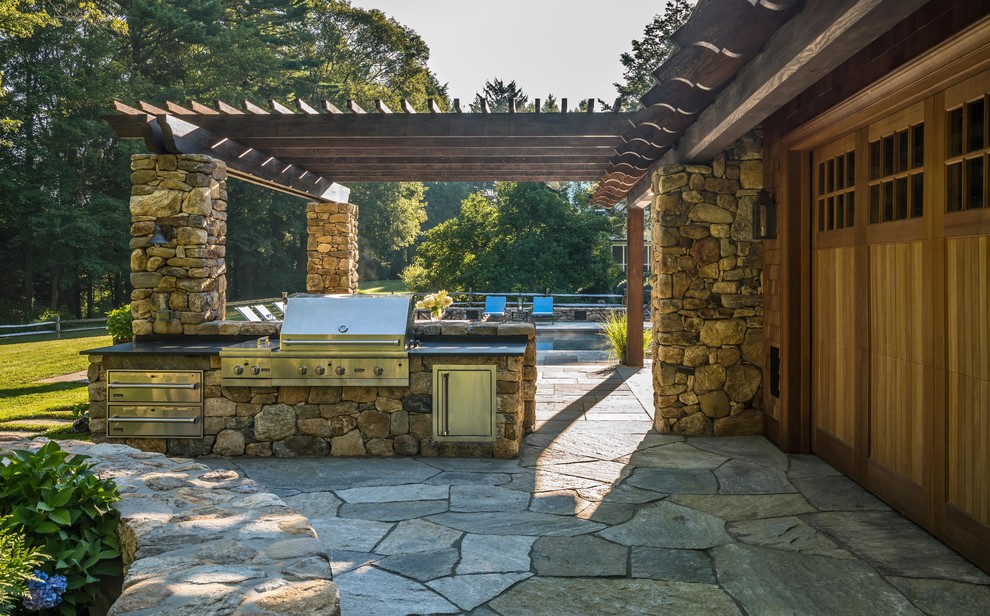 Immagine di un ampio patio o portico rustico dietro casa con pavimentazioni in pietra naturale e una pergola