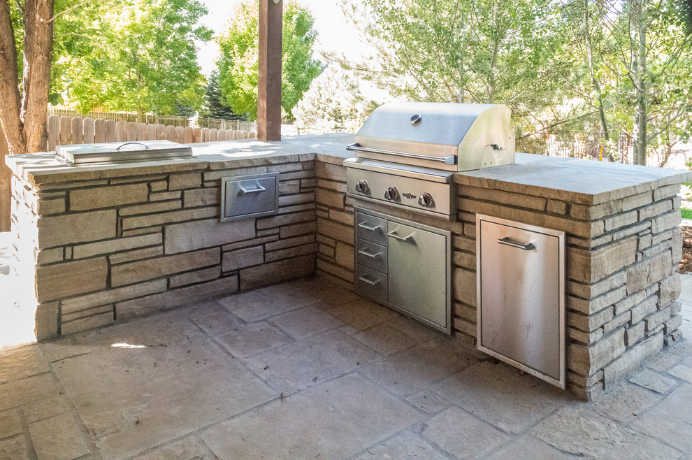 Large classic back patio in Denver with an outdoor kitchen and natural stone paving.