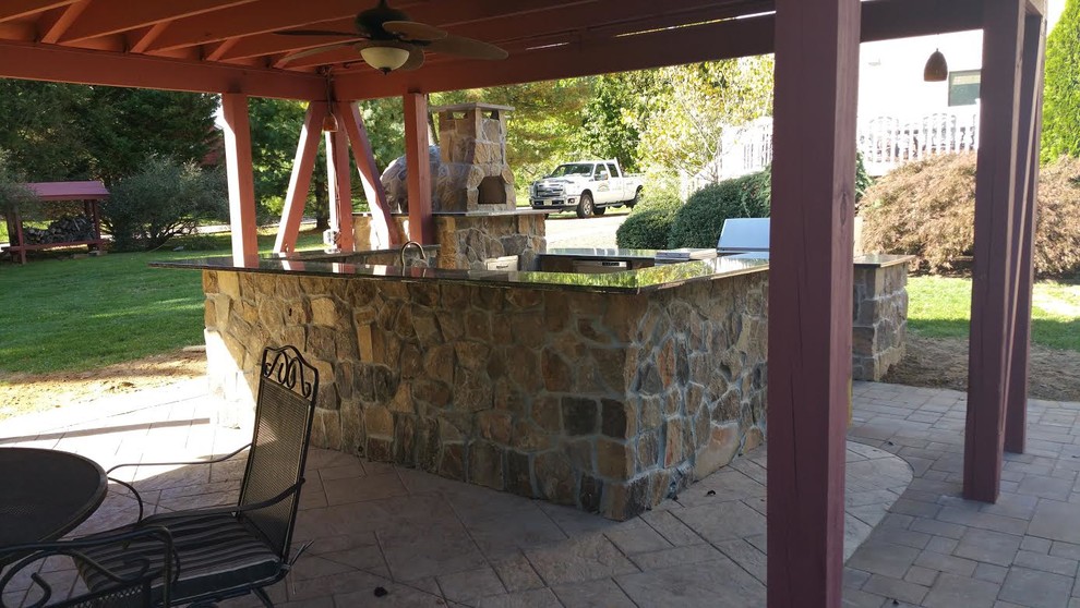 Réalisation d'une grande terrasse arrière champêtre avec une cuisine d'été, une dalle de béton et un gazebo ou pavillon.