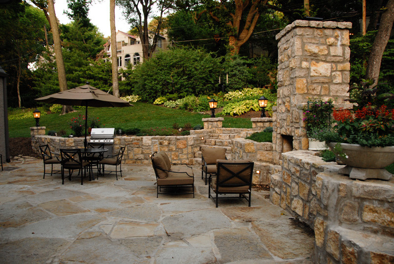 This is an example of a medium sized traditional back patio in Kansas City with a fire feature, natural stone paving and no cover.
