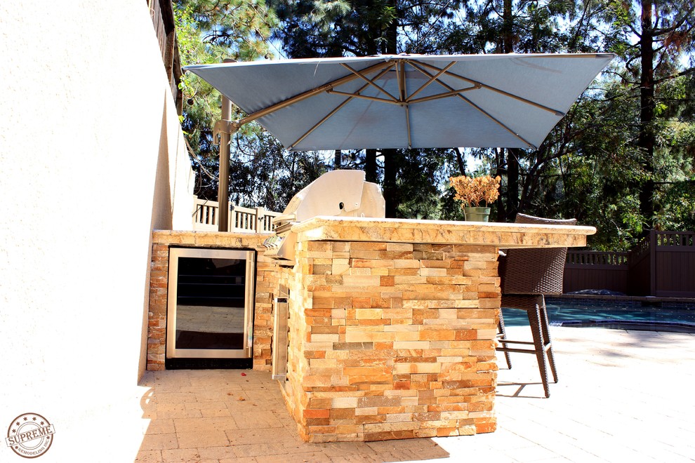 Modelo de patio mediterráneo de tamaño medio sin cubierta en patio trasero con cocina exterior y adoquines de piedra natural