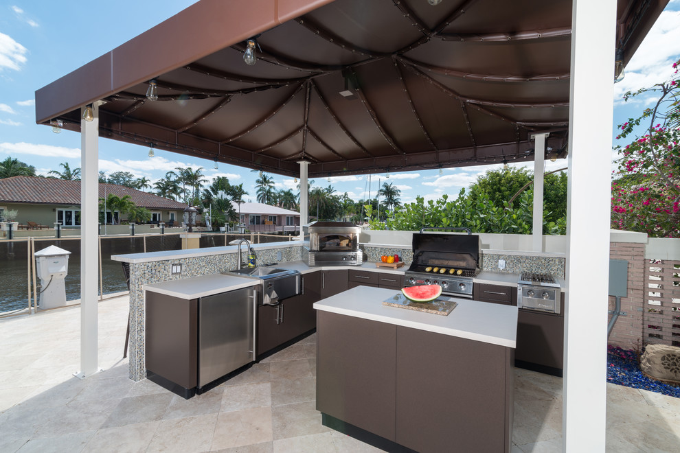 Photo of a small world-inspired back patio in Miami with an outdoor kitchen, an awning and brick paving.