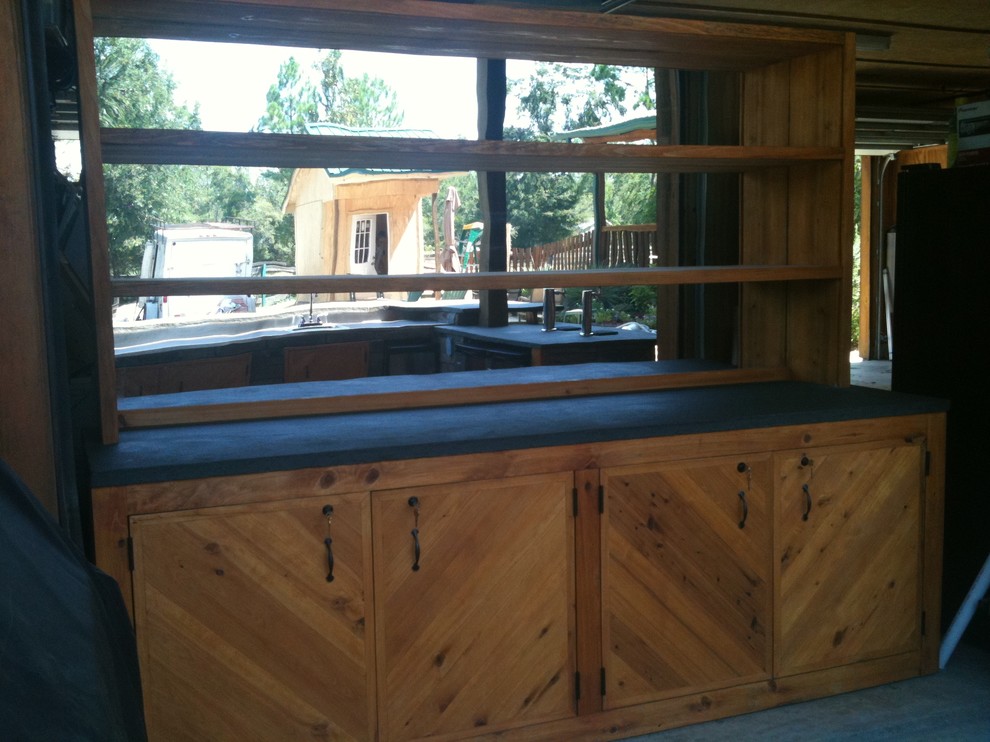Photo of a medium sized rustic back patio in Jacksonville with an outdoor kitchen, concrete slabs and a roof extension.
