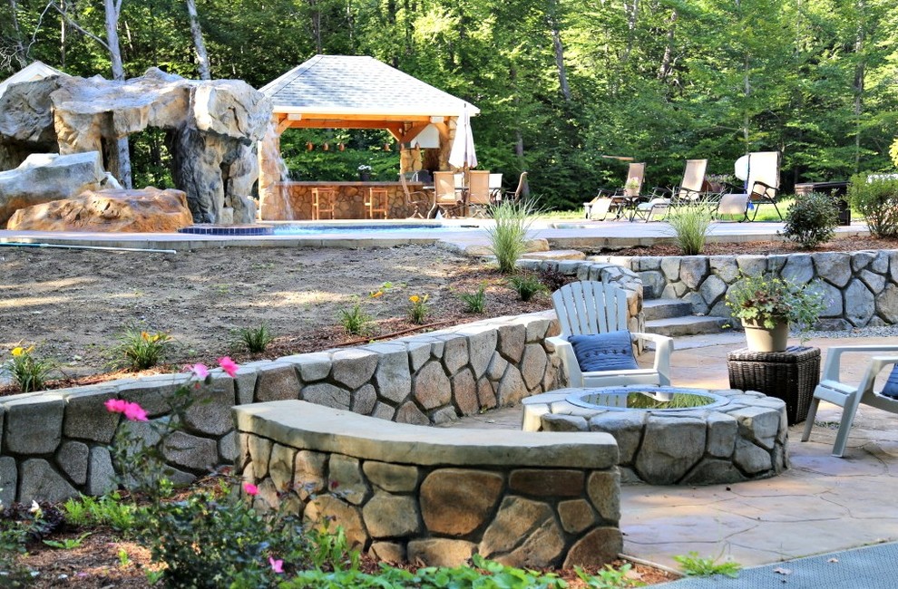 This is an example of a medium sized rustic back patio in Boston with an outdoor kitchen, natural stone paving and a pergola.