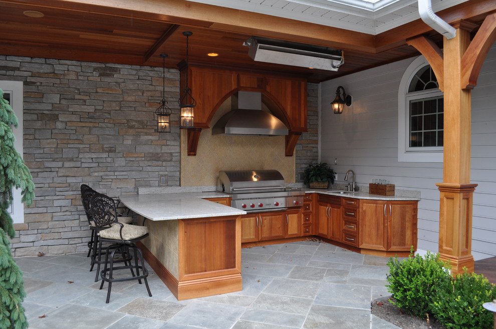 Photo of a large mediterranean back patio in Cleveland with an outdoor kitchen, natural stone paving and a roof extension.