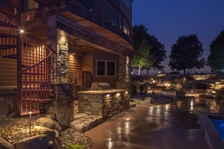 This is an example of a rustic back patio in Omaha with an outdoor kitchen.