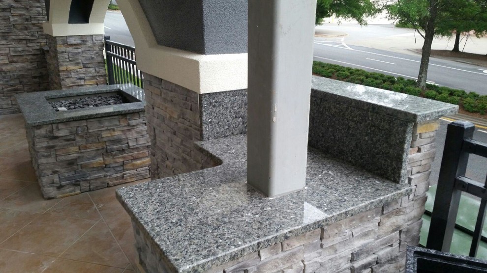 Photo of a medium sized contemporary front patio in Atlanta with a fire feature, brick paving and a roof extension.