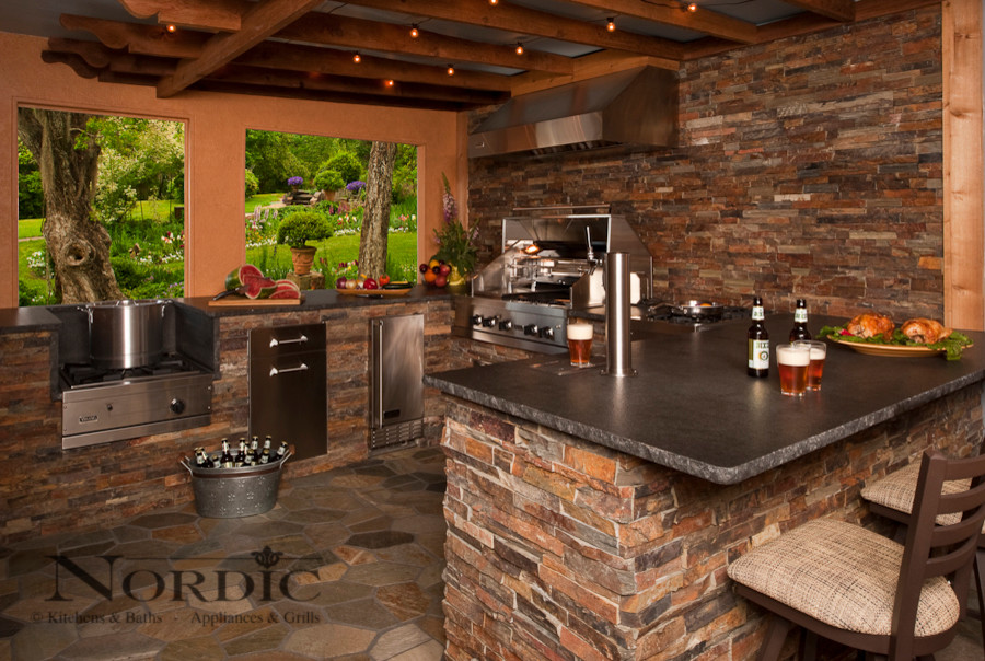 Patio kitchen - large traditional backyard stone patio kitchen idea in New Orleans with a roof extension