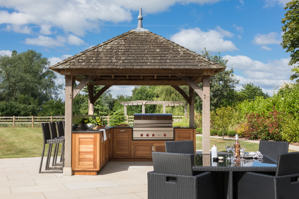 Design ideas for a medium sized contemporary back patio in Essex with natural stone paving, a pergola and a bbq area.