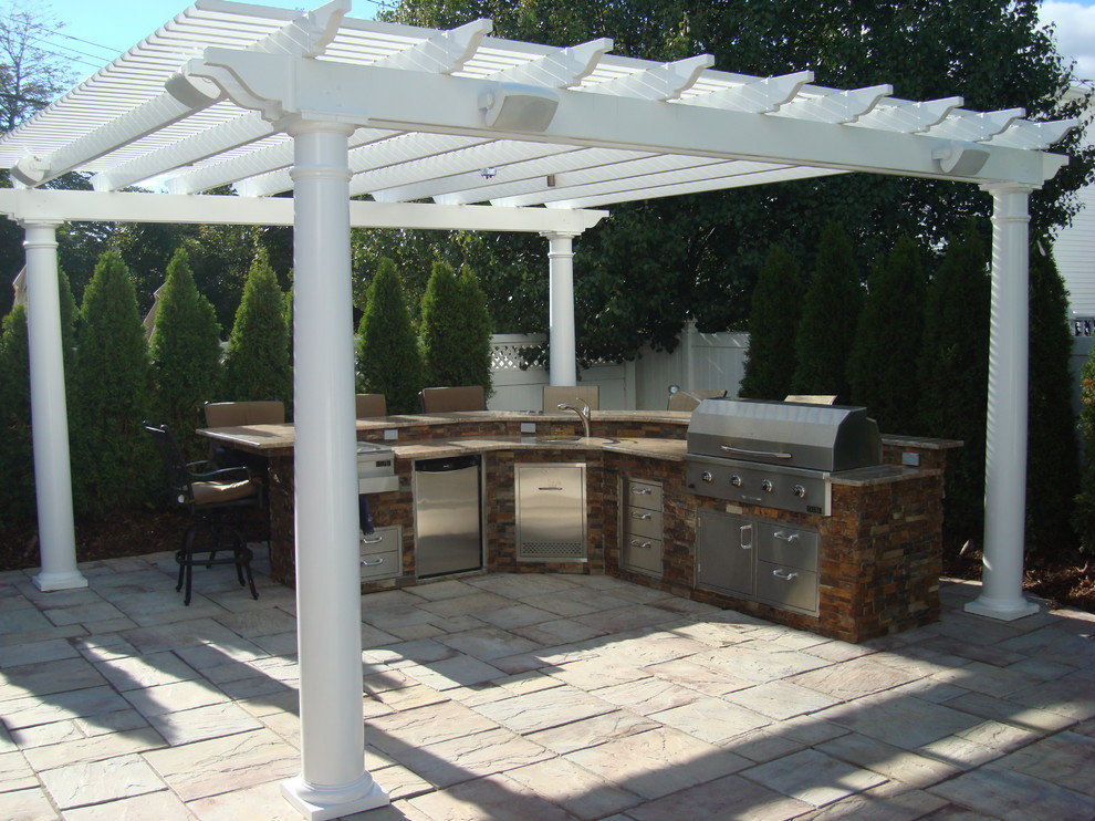 Cette photo montre une terrasse arrière chic de taille moyenne avec une cuisine d'été, du béton estampé et une pergola.