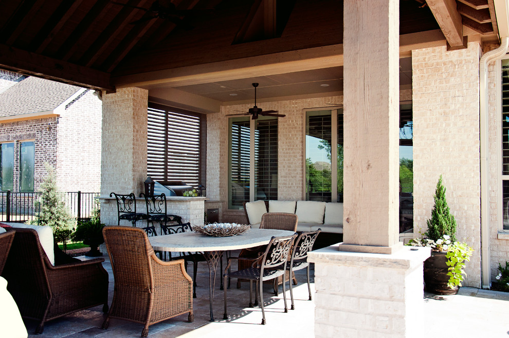 Foto di un patio o portico chic di medie dimensioni e dietro casa con pavimentazioni in pietra naturale e un tetto a sbalzo