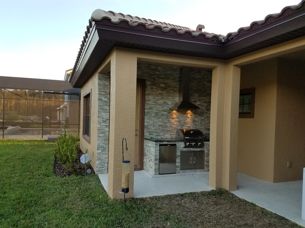 Kleiner, Überdachter Klassischer Patio hinter dem Haus mit Outdoor-Küche und Natursteinplatten in Tampa