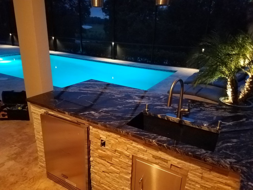 Mittelgroßer, Überdachter Uriger Patio hinter dem Haus mit Outdoor-Küche und Natursteinplatten in Tampa