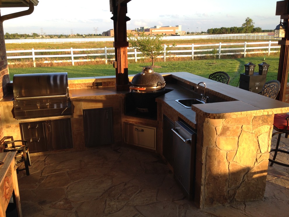Inspiration for a large craftsman backyard stone patio kitchen remodel in Dallas with a pergola