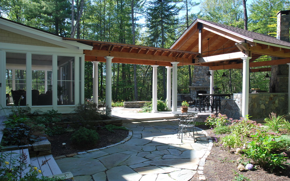 Esempio di un patio o portico tradizionale dietro casa con pavimentazioni in pietra naturale e un tetto a sbalzo