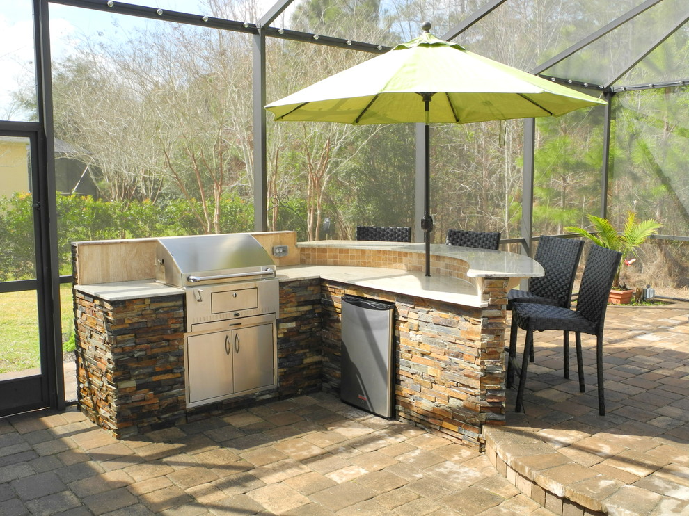 Cette photo montre une grande terrasse arrière chic avec une cuisine d'été, des pavés en béton et un auvent.
