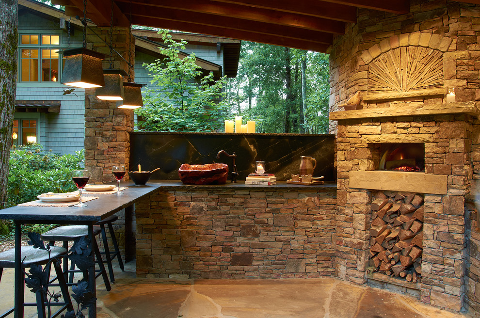 Inspiration for a mid-sized rustic backyard stone patio kitchen remodel in Other with a gazebo
