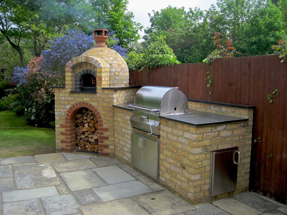 Cette photo montre une terrasse arrière chic de taille moyenne avec une cuisine d'été, des pavés en brique et aucune couverture.