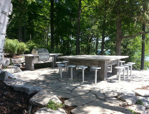 Mid-sized elegant backyard stone patio kitchen photo in Other with no cover