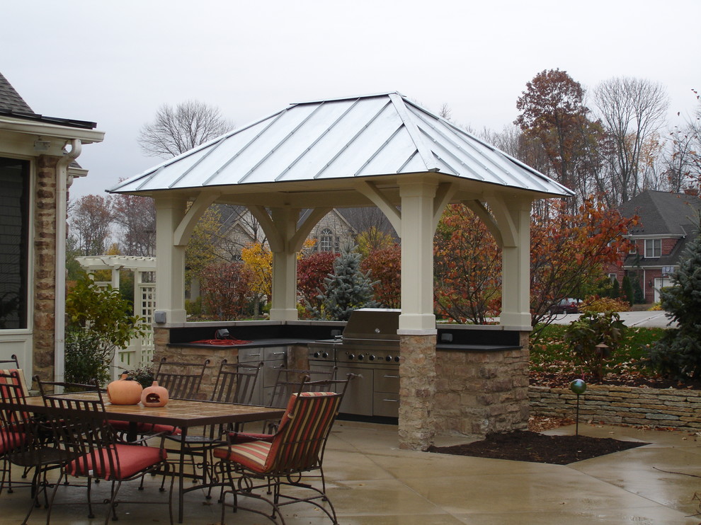 Ispirazione per un patio o portico classico dietro casa con cemento stampato e un parasole