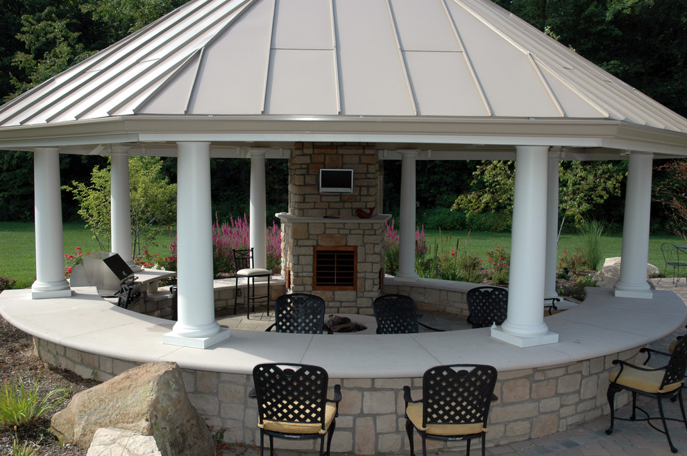 Immagine di un patio o portico tradizionale dietro casa con pavimentazioni in cemento e un gazebo o capanno