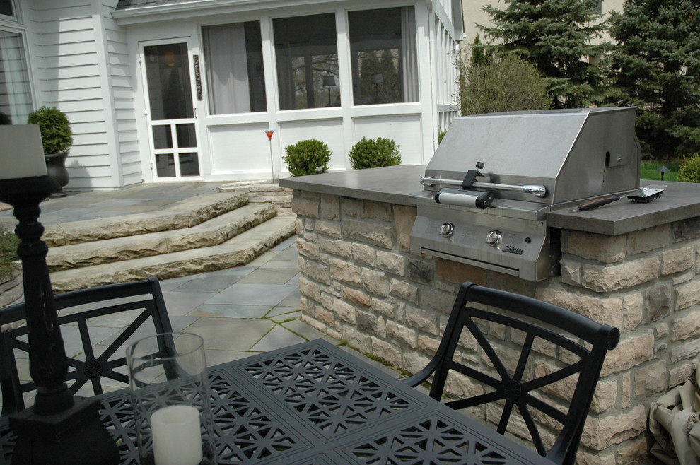 Ejemplo de patio clásico sin cubierta en patio trasero con cocina exterior y adoquines de piedra natural