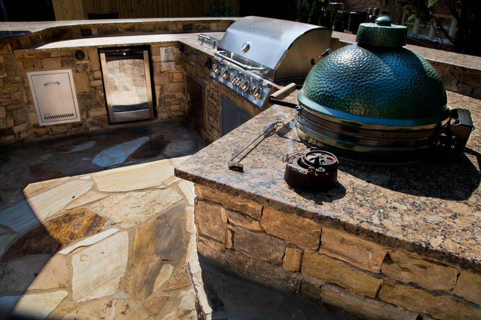 Réalisation d'une terrasse arrière tradition de taille moyenne avec une cuisine d'été, des pavés en pierre naturelle et aucune couverture.