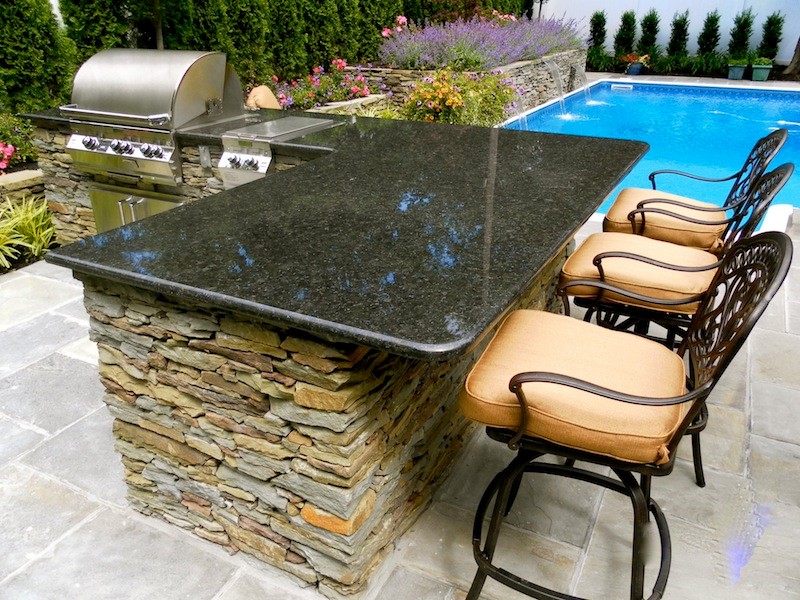 Example of a minimalist backyard stone patio kitchen design in New York with no cover