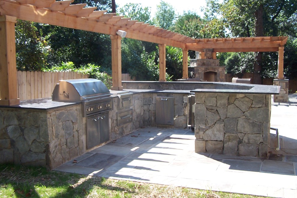 Example of a mid-sized classic backyard stone patio kitchen design in DC Metro with a pergola