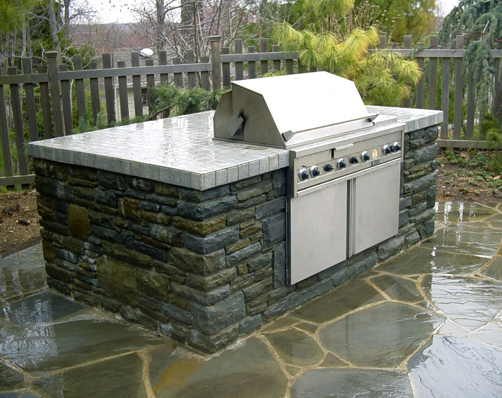 Modelo de patio de estilo americano sin cubierta en patio trasero con cocina exterior y adoquines de hormigón