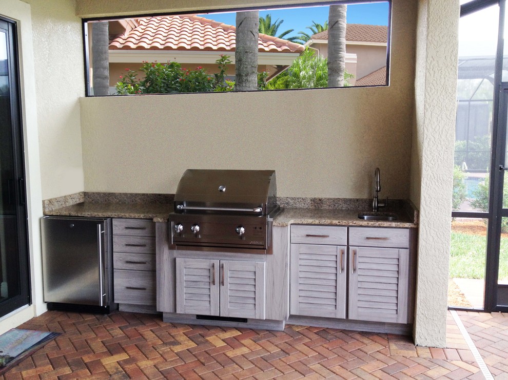 Cette photo montre une grande terrasse arrière exotique avec une cuisine d'été, des pavés en béton et une extension de toiture.
