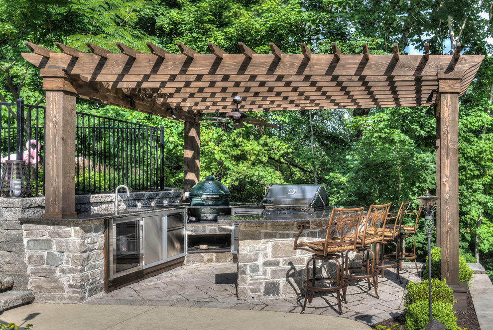 Rustic back patio in St Louis with an outdoor kitchen, stamped concrete and a pergola.