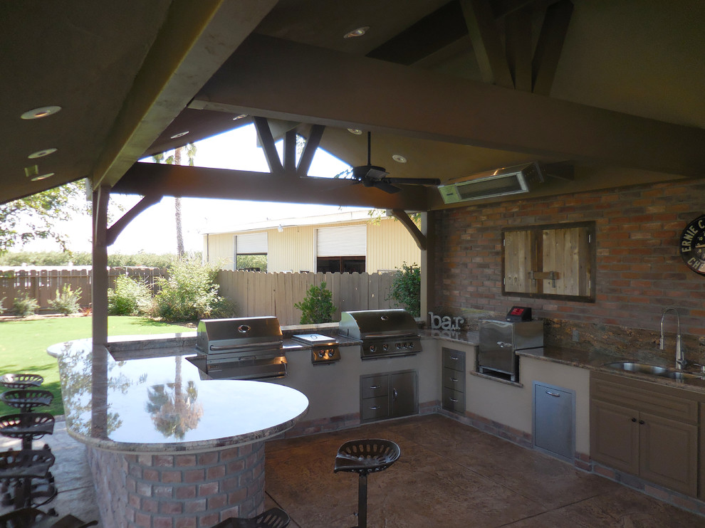 Inspiration pour une grande terrasse arrière chalet avec une cuisine d'été, du béton estampé et une pergola.