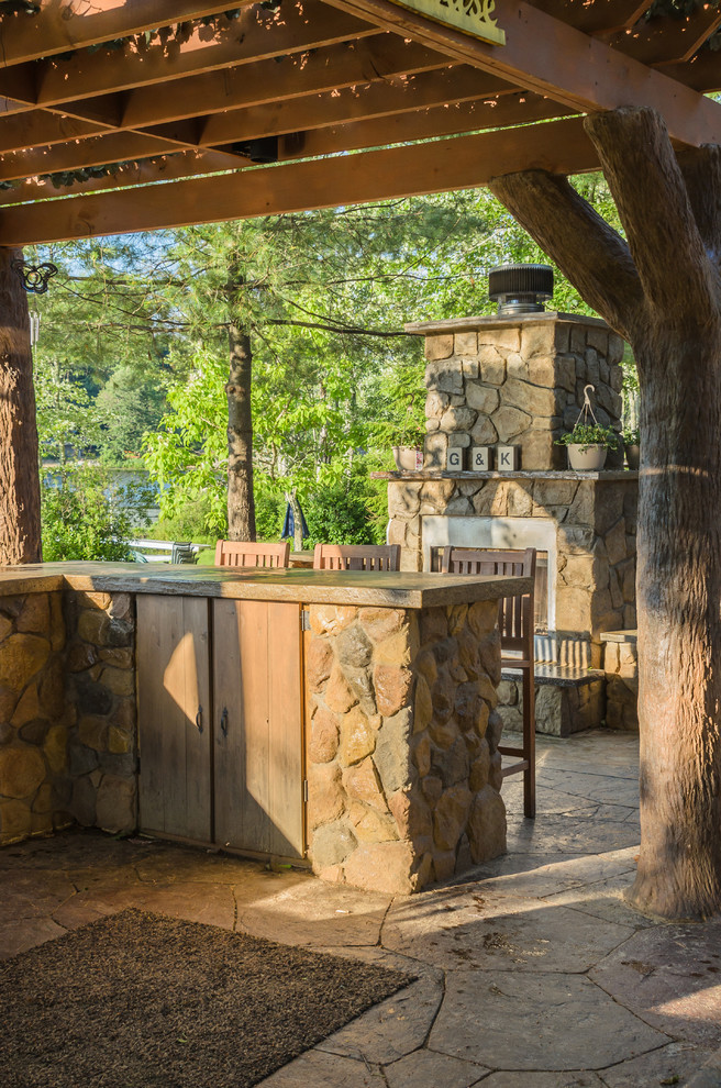 Diseño de patio rústico grande en patio trasero con cocina exterior, adoquines de piedra natural y pérgola