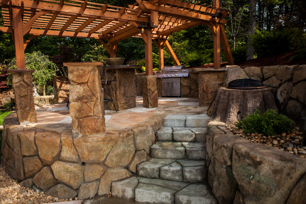 Cette photo montre une grande terrasse arrière montagne avec une cuisine d'été, des pavés en pierre naturelle et une pergola.