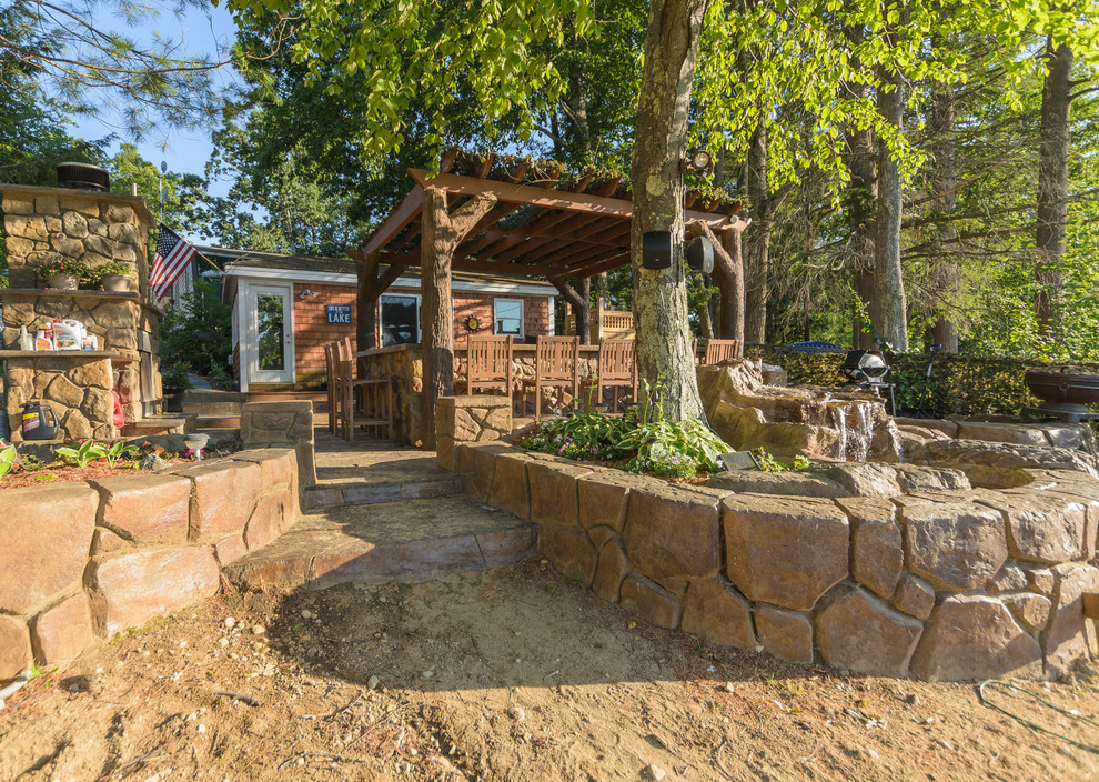 Foto di un grande patio o portico stile rurale dietro casa con pavimentazioni in pietra naturale e una pergola