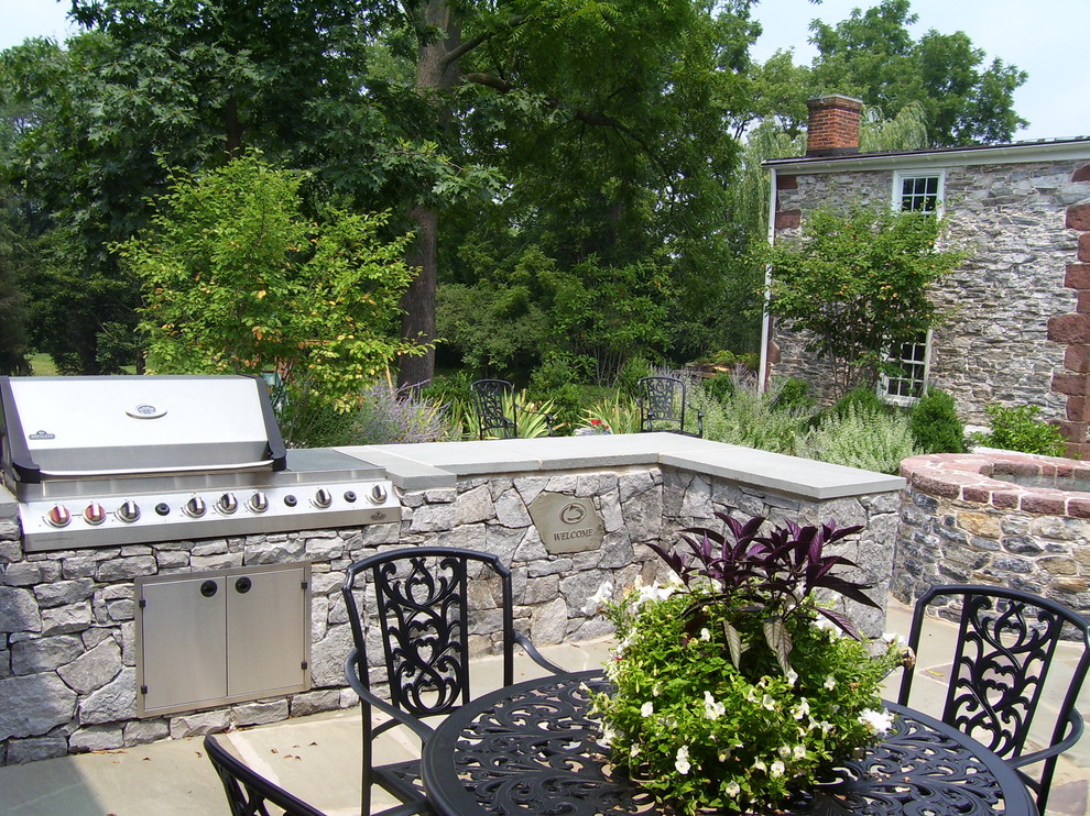 Example of a large classic backyard stone patio kitchen design in Philadelphia