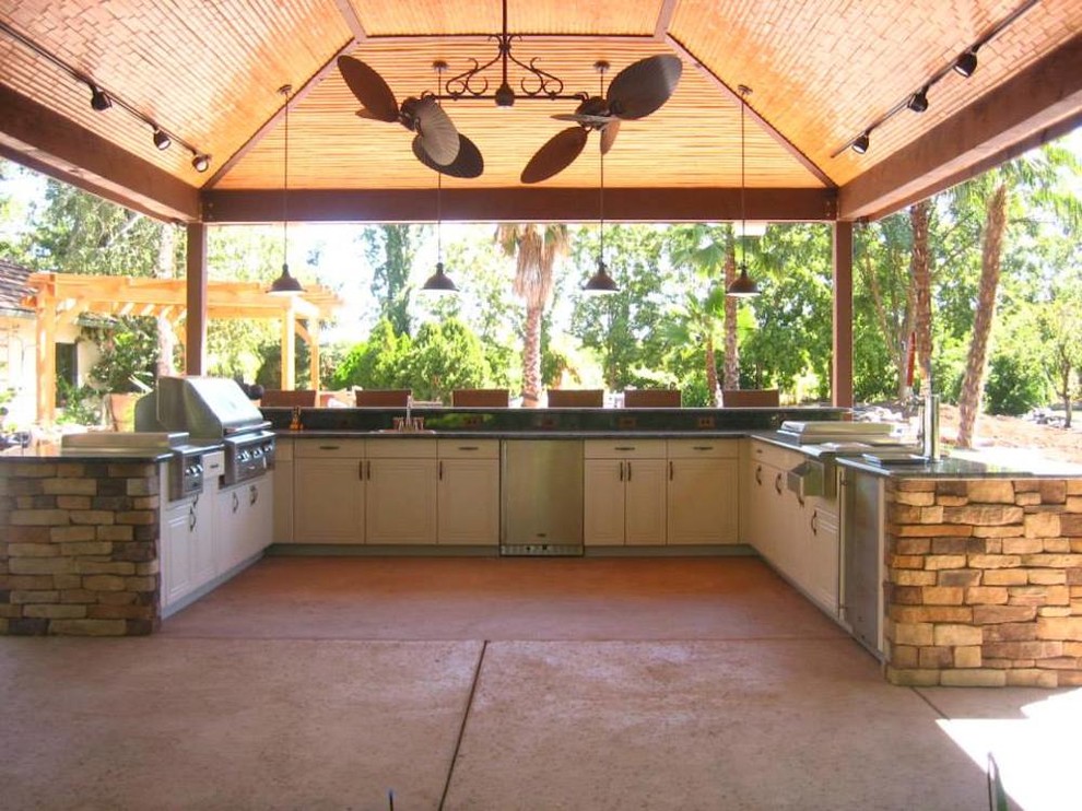 This is an example of a large back patio in Houston with an outdoor kitchen, brick paving and a pergola.