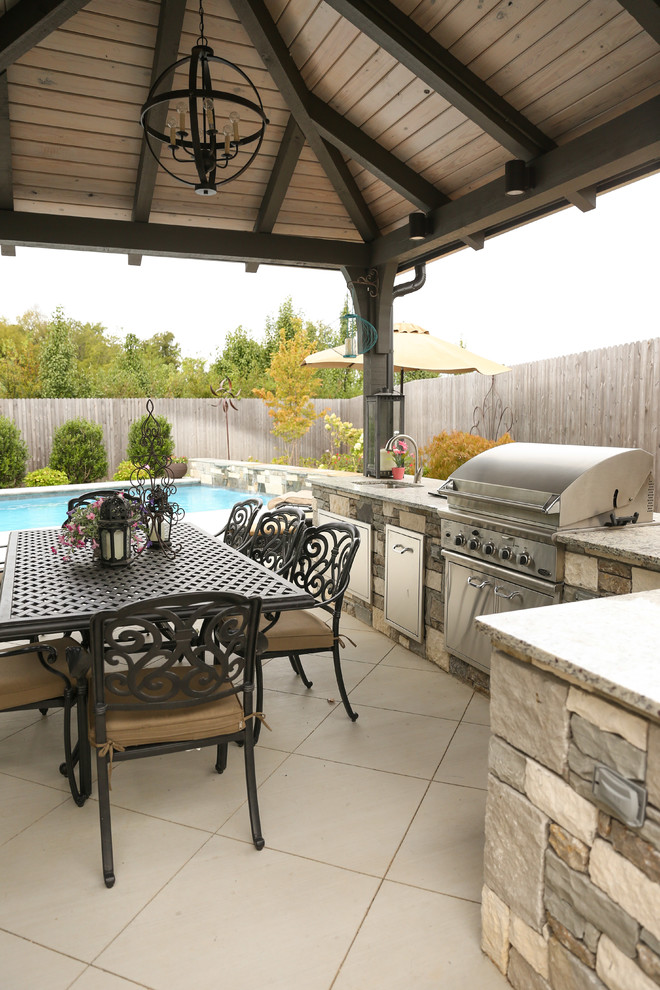 Cette photo montre une grande terrasse arrière tendance avec une cuisine d'été, une dalle de béton et une pergola.