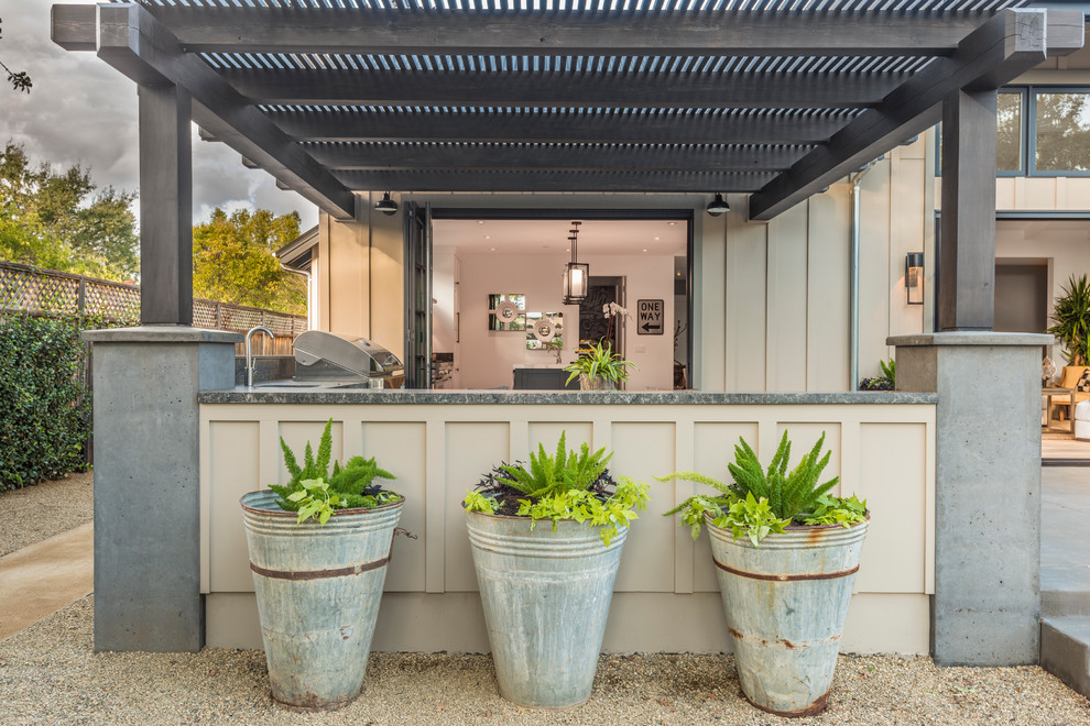 Cette image montre une grande terrasse arrière rustique avec une cuisine d'été, une dalle de béton et une pergola.