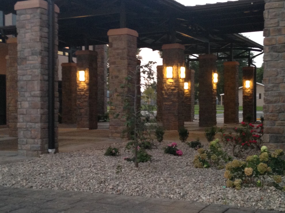 Immagine di un grande patio o portico rustico dietro casa con pavimentazioni in pietra naturale e un tetto a sbalzo