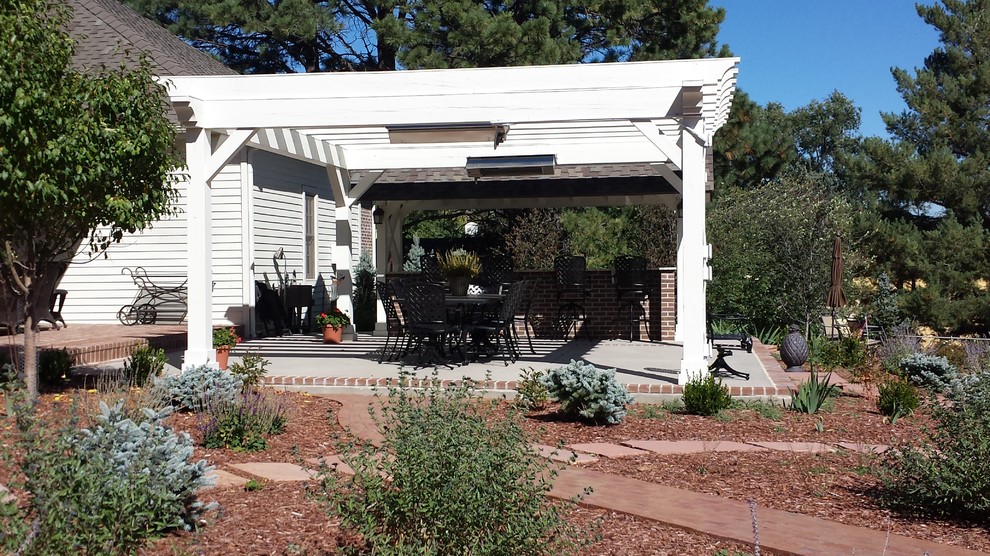 Imagen de patio clásico de tamaño medio en patio trasero con cocina exterior, losas de hormigón y pérgola