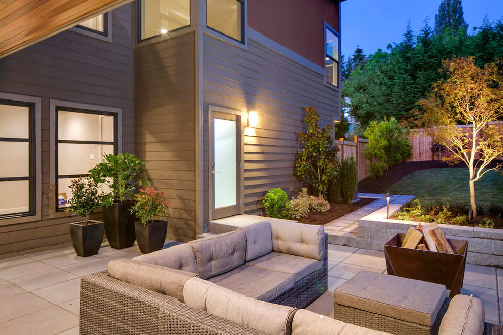 Foto di un patio o portico design dietro casa con un focolare, pavimentazioni in cemento e un tetto a sbalzo