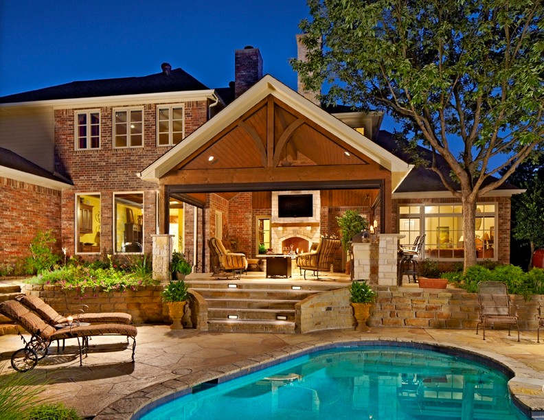 Exemple d'une grande terrasse arrière chic avec une cuisine d'été, des pavés en pierre naturelle et une extension de toiture.