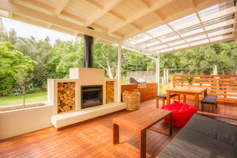 Idées déco pour une terrasse en bois contemporaine avec un foyer extérieur et une extension de toiture.