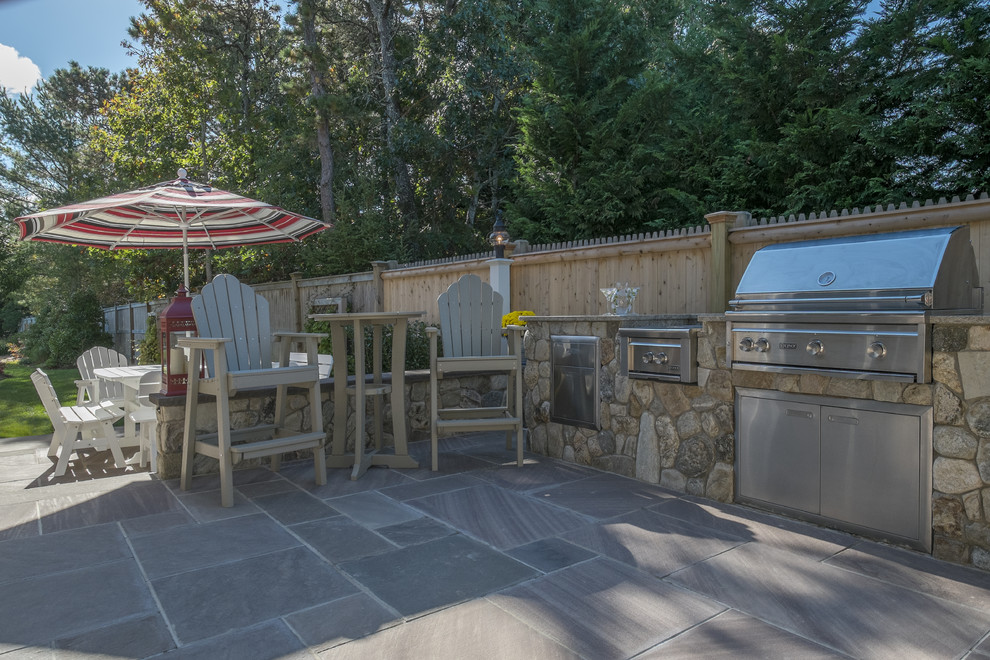 Photo of a small beach style back patio in Boston with an outdoor kitchen, natural stone paving and no cover.