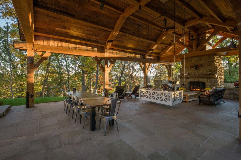 Cette image montre une très grande terrasse arrière chalet avec une cuisine d'été et des pavés en pierre naturelle.